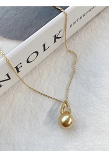Detail of a gold S925 sterling silver necklace featuring a pearl pendant and micro-set diamonds