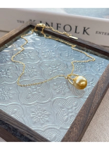 Detailed view of the gold imitation pearl necklace resting on a vintage wooden glass tray