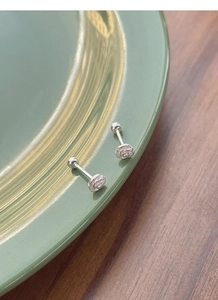 Detailed view of silver camellia stud earrings with screw ball back on a ceramic plate