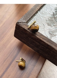 Macro detail of S925 silver tiger eye stud earrings on a vintage wooden box