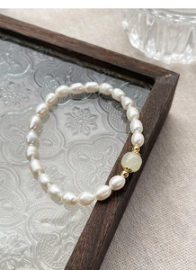 Macro shot of S925 silver freshwater pearl bracelet with green jade bead on wooden tray