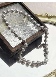 Detailed view of grey pearl necklace with a diamond-encrusted figure-eight buckle