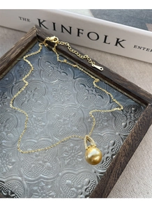 Detail of a gold pearl necklace with micro-pave pendant on vintage glass decor