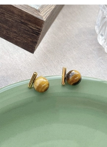Macro detail of S925 silver tiger eye stone studs with gold geometric bar design