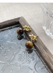 Detail of S925 silver knot stud earrings with polished gold finish and tiger eye stone