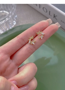 Detailed view of gold wheat leaf stud earrings with marquise zirconia held by hand