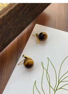 Close-up of S925 silver tiger eye stone earrings with a polished gold finish