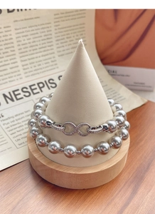 Detail view of double-layer dark grey pearl necklace with crystal infinity buckle