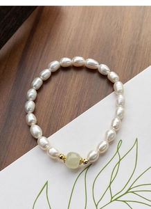 Detail of freshwater pearl bracelet with green jade bead on a minimalist display card