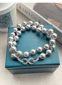 Detail view of S925 silver infinity clasp with micro-set diamonds on grey pearl necklace