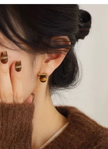 Detail of S925 silver tiger eye stud earring worn by model in a minimalist gold finish style