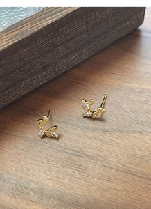 Detail shot of silver wheat wreath stud earrings with marquise zircons on a wooden surface