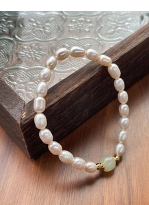 Detail of S925 silver natural freshwater pearl bracelet with green jade and gold accents