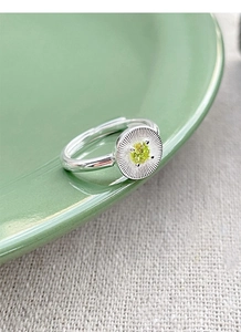 Détail macro d'une bague en argent avec texture soleil et zircon vert brillant