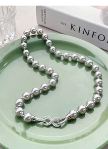Macro shot of silver infinity clasp with micro-diamonds on grey pearl necklace