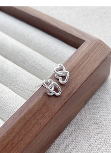 Detailed macro of S925 sterling silver interlocking double heart earrings on beige velvet