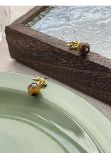 Detail of vintage gold knot earrings with polished brown tiger eye stone beads on display