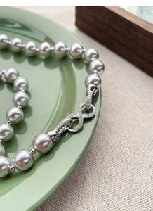 Detailed close-up of dark grey pearls with an infinity clasp set in silver with zircons