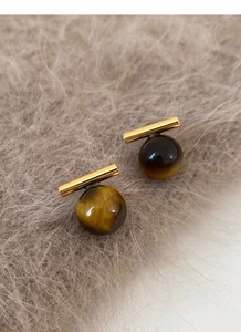 Detailed close-up of S925 silver tiger eye stud earrings on soft grey plush fabric