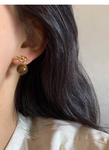 Close-up of S925 silver golden knot earring with a polished tiger eye stone pendant