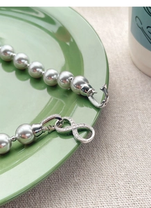 Macro detail of S925 silver infinity clasp with tiny zircons on grey pearl necklace
