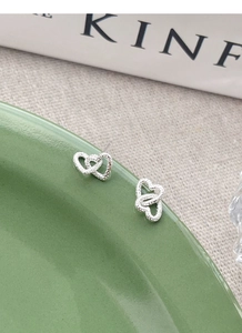 Detailed view of S925 silver stud earrings featuring interlocking textured double hearts