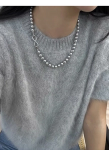 Detailed view of silver bead necklace with a crystal-encrusted infinity symbol clasp