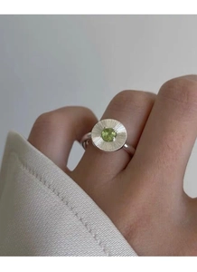 Gros plan d'une bague en argent S925 avec texture rayée et zircon vert rond