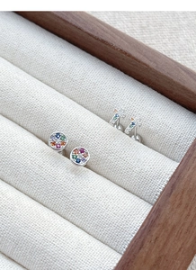 Close-up of S925 sterling silver cross and round studs with colorful crystals in a jewelry box