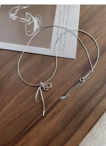 Macro detail of S925 sterling silver knotted bow pendant with delicate snake chain