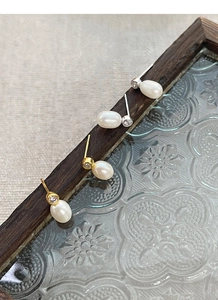 Vue détaillée des boucles d'oreilles perles argent et or avec zircons sur cadre vintage
