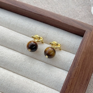 S925 silver tiger eye stud earrings with golden knot design in jewelry display case