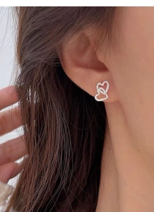 Close-up of interlocking double heart silver earrings on model showcasing textured finish