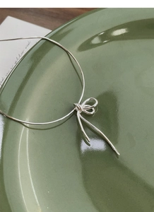 Detail of S925 sterling silver bow knot pendant on a slim snake chain necklace