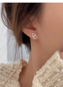 Close-up of S925 sterling silver interlocking double heart earrings worn by a model