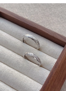 Close-up of S925 sterling silver couple rings with frosted starlight texture in a wooden box