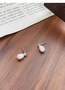 Détail de boucles d'oreilles perles d'eau douce en forme de goutte sur bois sombre