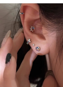 Macro shot of S925 silver stud earrings with colorful zircon and cross patterns on ear