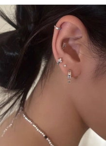 Detail showing colorful zircon cross studs and rainbow hoops in a multi-piercing ear arrangement