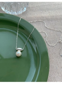 Close-up of S925 silver minimalist necklace with round white pearl and olive pendant