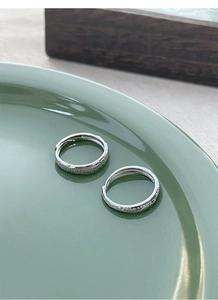 Close-up of S925 sterling silver couple rings with frosted finish on green ceramic plate
