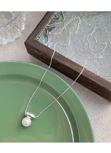 Detail of S925 sterling silver chain with elegant white pearl pendant on a ceramic plate