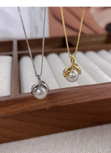Detail of silver and gold pearl necklaces with leaf-shaped clasps on a jewelry tray