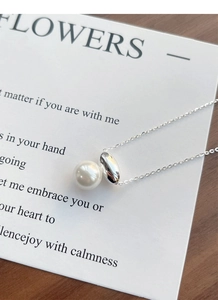 Close-up of S925 sterling silver necklace with white pearl and sleek metallic bean pendant