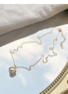 Detailed view of single pearl pendant on gold chain with lobster clasp and extension