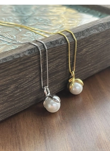 Close-up of gold and silver S925 necklaces with white pearls on elegant box chains