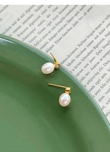 Détails de boucles d'oreilles en argent S925 avec perles et diamants sur une assiette verte