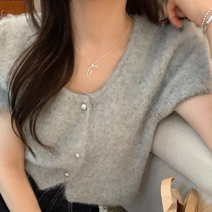 Minimalist S925 sterling silver bow necklace worn with a grey plush cardigan