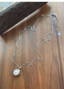 Detailed view of the S925 sterling silver hallmark on a delicate pearl necklace chain