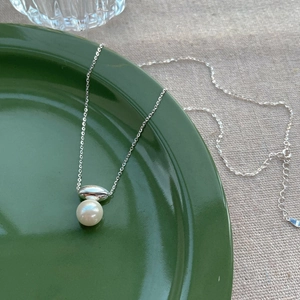Elegant S925 sterling silver necklace with a white pearl pendant on a green ceramic plate